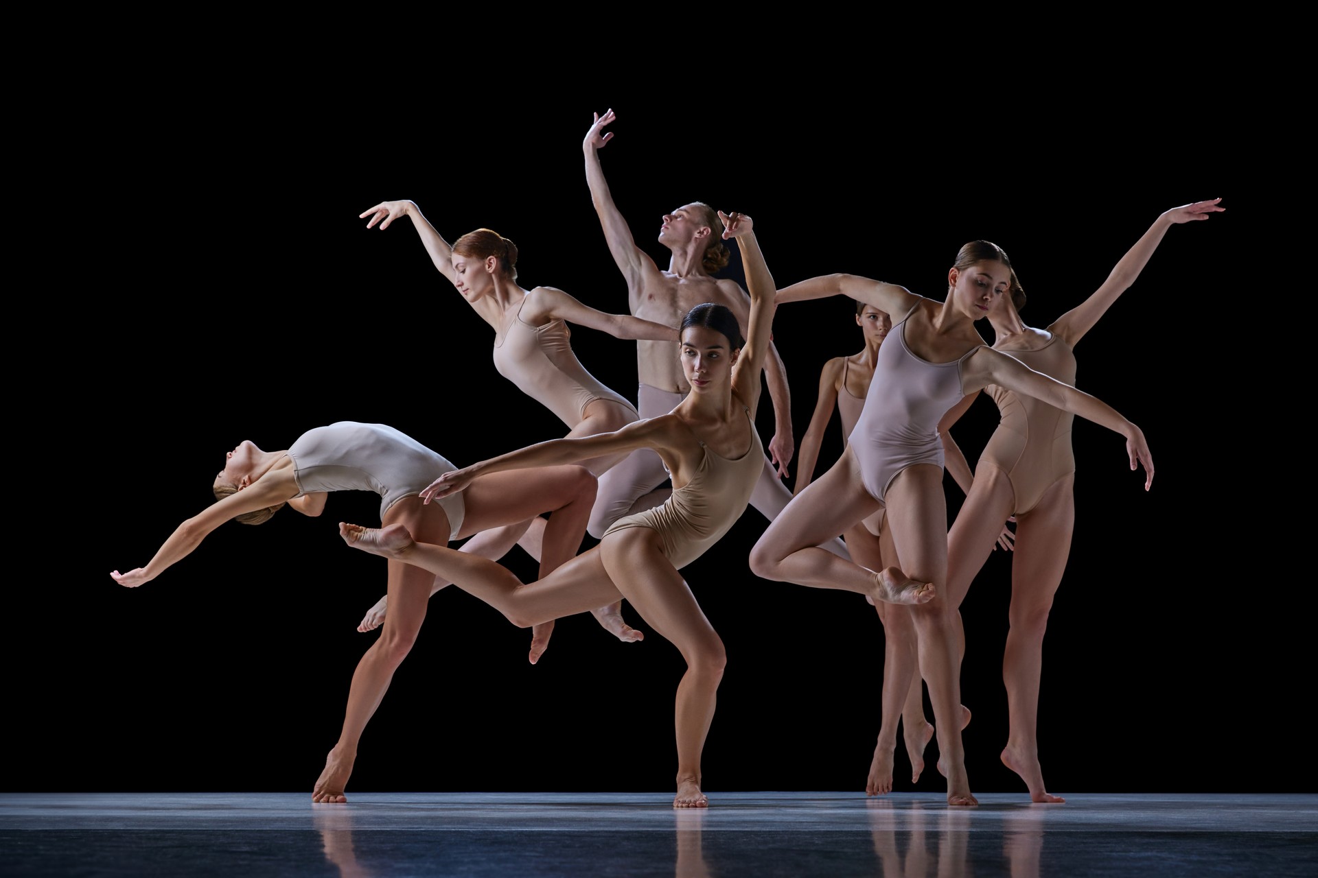 Tender, elegant young people, ballet dancers making beautiful performance on stage against black background.